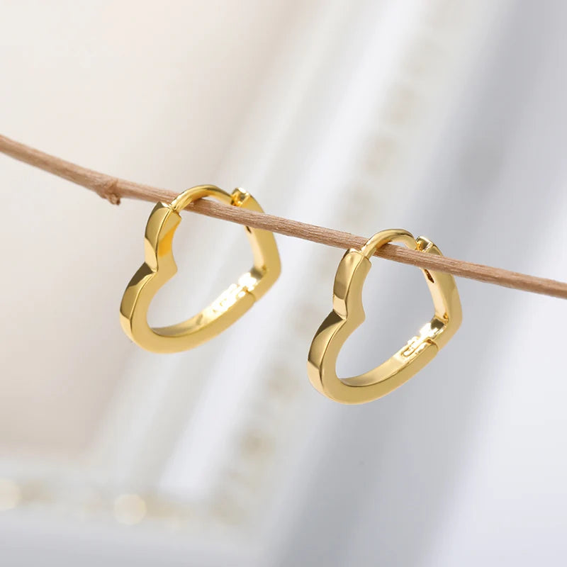 Chunky gold huggie earrings with a heart drop design, showcasing a sleek and minimalist style.