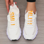 Lightweight white knitted performance sneakers with orange text, featuring a flexible outsole and slip-on fit.