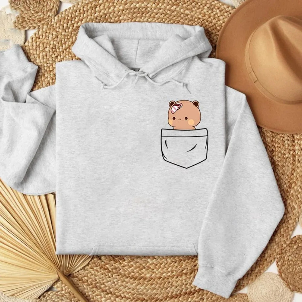 Light gray oversized hoodie featuring a cute bear graphic peeking from a front pocket. Soft, cozy material.