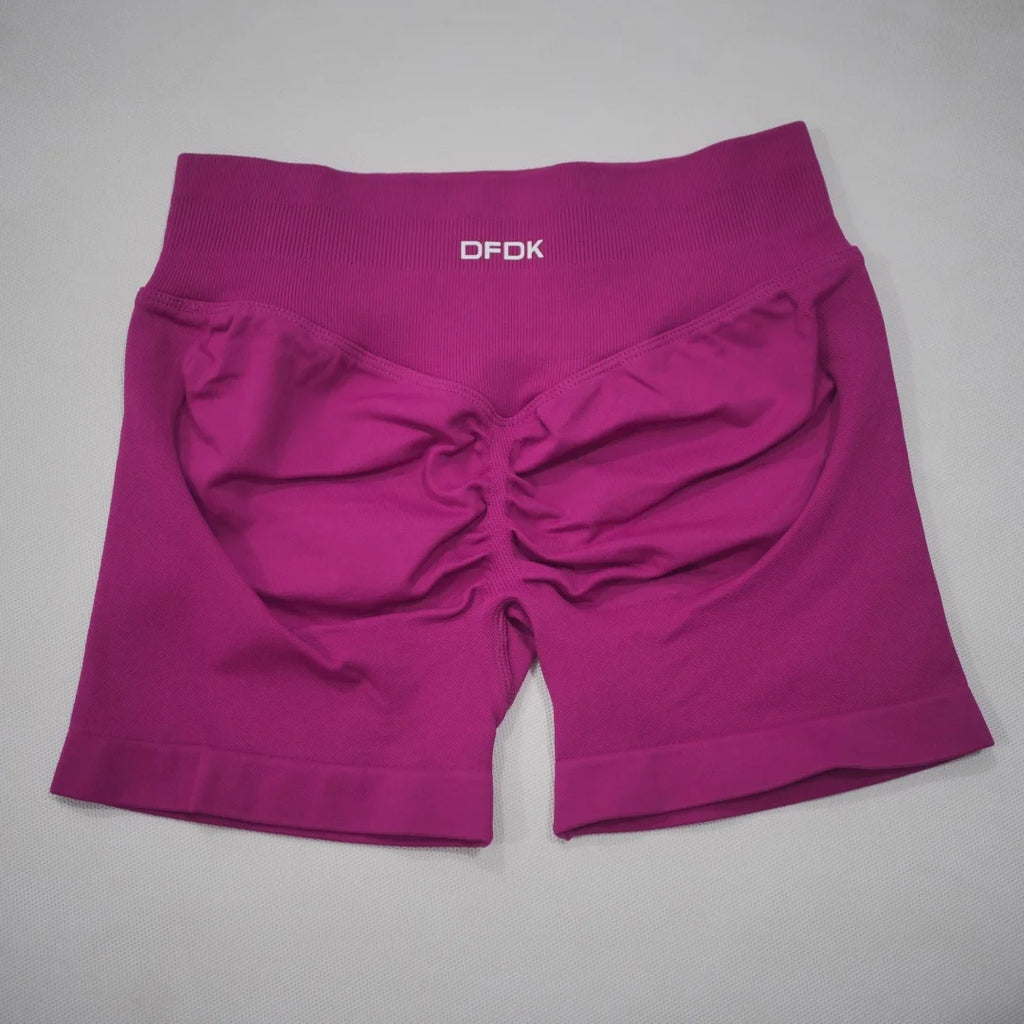 High-waisted gym shorts in a vibrant fuchsia color with a scrunch-butt design and wide, seamless waistband.