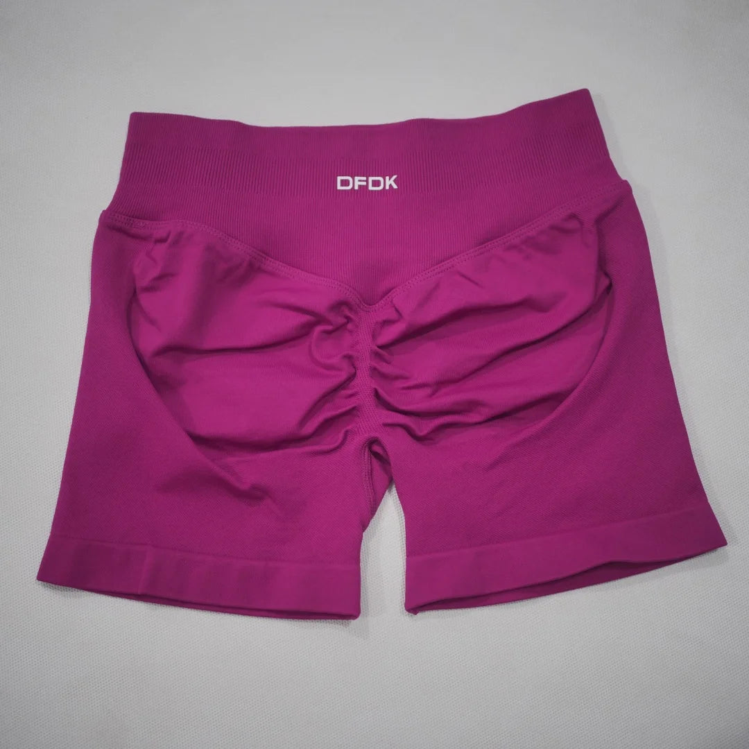High-waisted gym shorts in a vibrant fuchsia color with a scrunch-butt design and wide, seamless waistband.