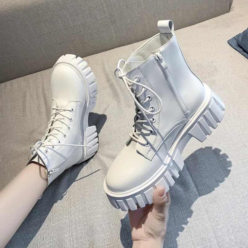 Chunky white LOVORA™ Combat Matrix boots with thick platform soles and lace-up design, shown being held against a light gray background.