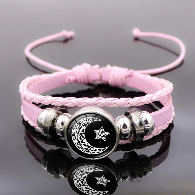 Multi-layered leather bracelet set featuring pink braided straps and a round black celestial token with star design.