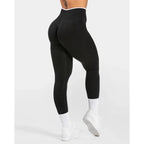 High-waisted black seamless leggings with an ultra-wide waistband, shown worn from the side with white socks and shoes.