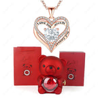 Red heart pendant necklace with crystal center, packaged with a red teddy bear and gift boxes.