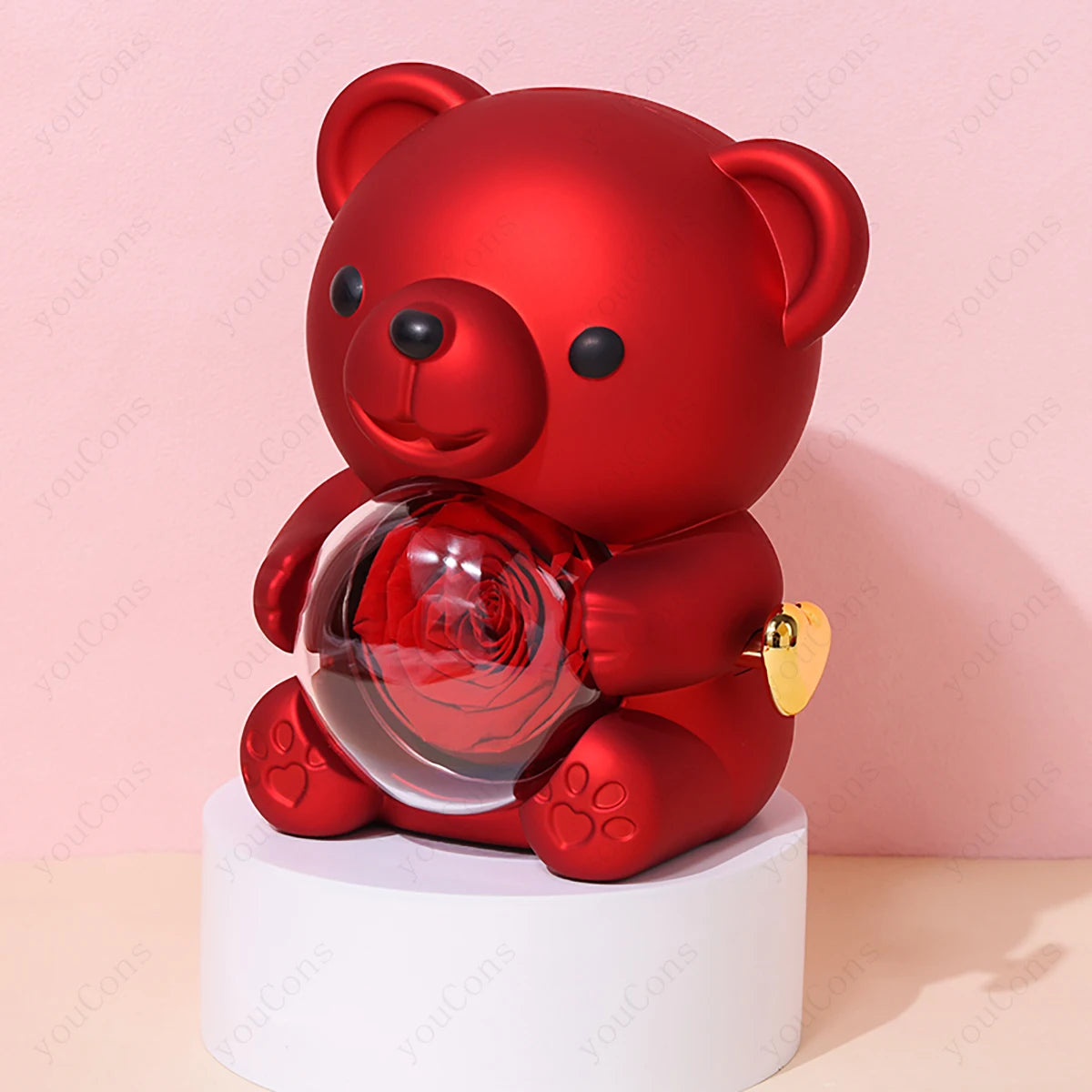 A red teddy bear holding a crystal sphere containing a red rose, displayed on a white pedestal against a pink background.