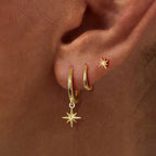Gold geometric drop earrings and a star stud earring worn in a model's ear, showcasing a mix of minimalist styles.