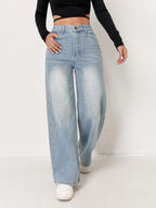 Light wash, high-waisted wide-leg denim jeans worn with a fitted black long-sleeve top and white sneakers.