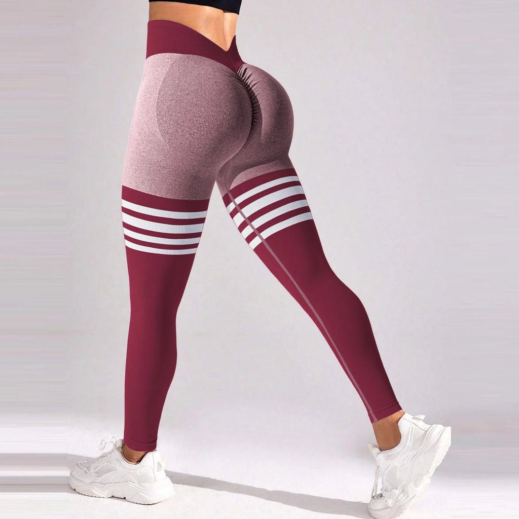 High-rise seamless leggings in burgundy and gray with white varsity stripes and a deep V-back contour, paired with white sneakers.