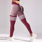 High-rise seamless leggings in burgundy and gray with white varsity stripes and a deep V-back contour, paired with white sneakers.