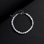 Unisex bracelet featuring irregular luster oval pearls with a silver-toned adjustable clasp on a textured black background.