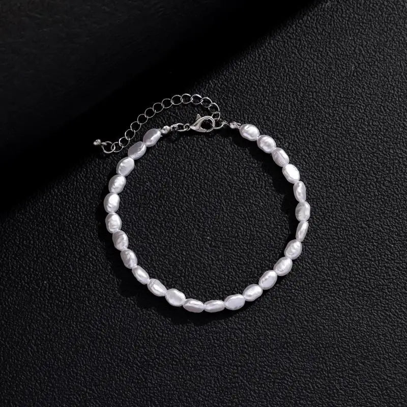 Unisex bracelet featuring irregular luster oval pearls with a silver-toned adjustable clasp on a textured black background.