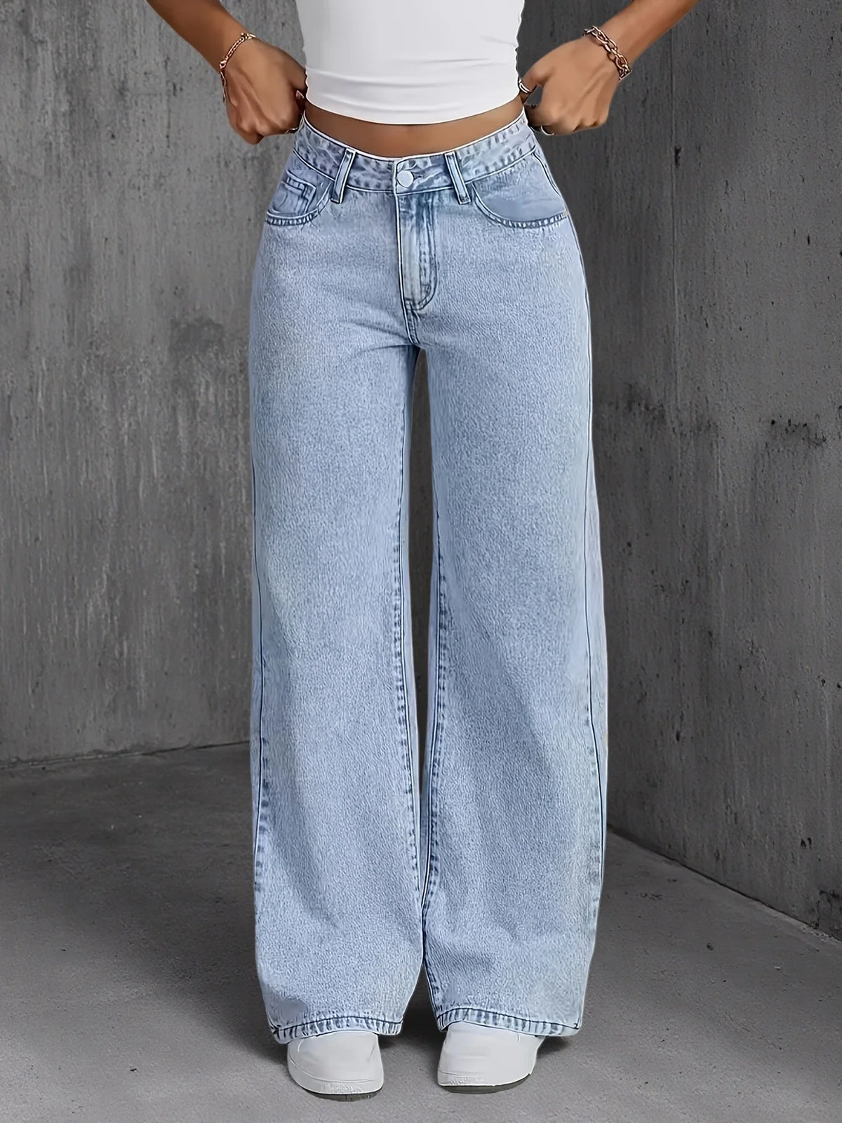 Light wash high-waisted wide-leg denim jeans featuring a relaxed fit and classic pockets, styled with a fitted white top.