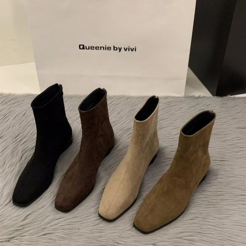 Four pairs of LOVORA™ Premium Suede Back-Zipper Ankle Boots in black, brown, beige, and olive green, presented on a textured gray surface.