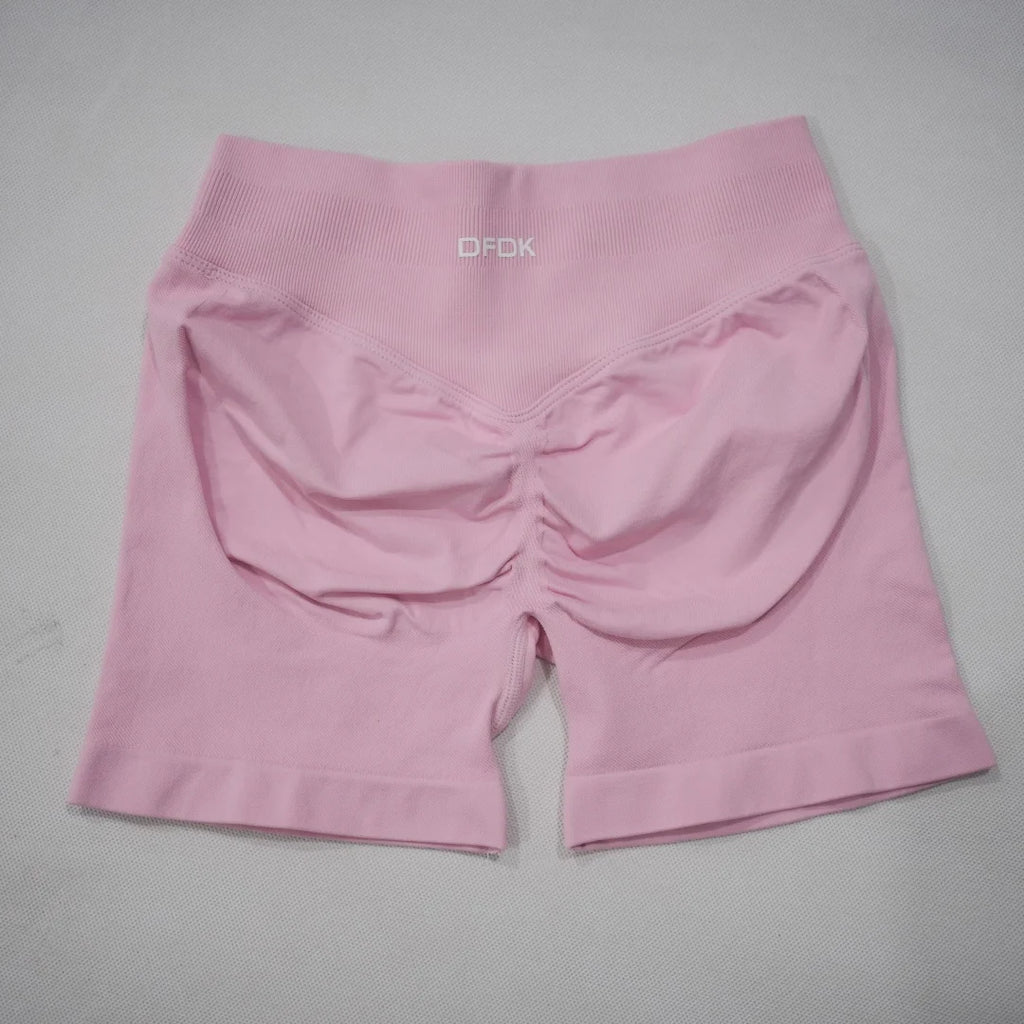 High-waisted gym shorts in light pink featuring a scrunch-butt design and a wide elastic waistband for comfort.