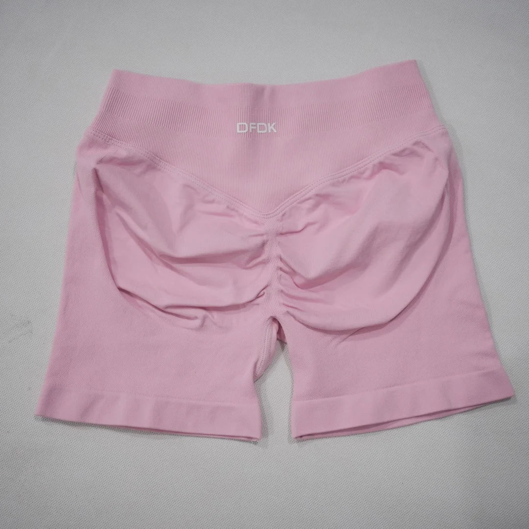 High-waisted gym shorts in light pink featuring a scrunch-butt design and a wide elastic waistband for comfort.