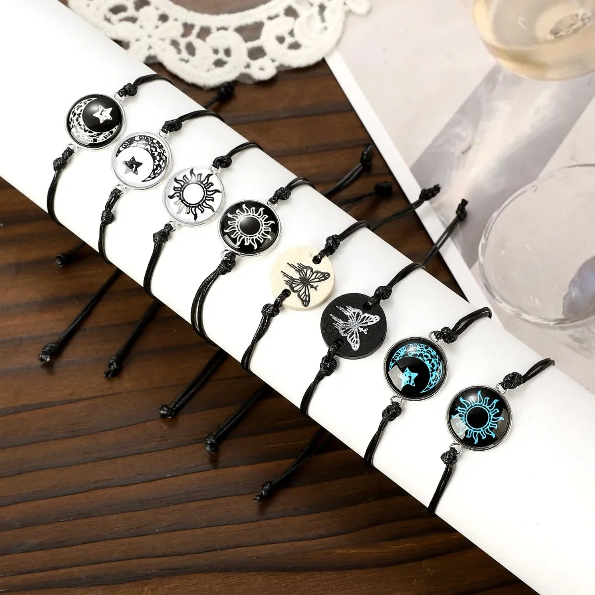 Luminous glow-in-the-dark bracelet set featuring black nylon ropes and celestial Sun and Moon charms. Adjustable fit.