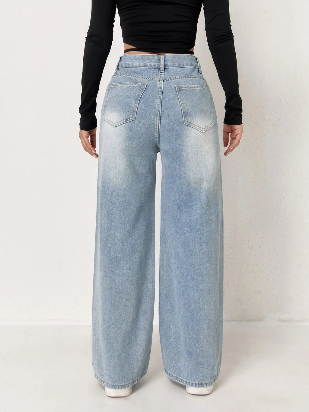 Light wash, high-waisted wide-leg denim jeans with a relaxed fit, worn with a black long-sleeve top.