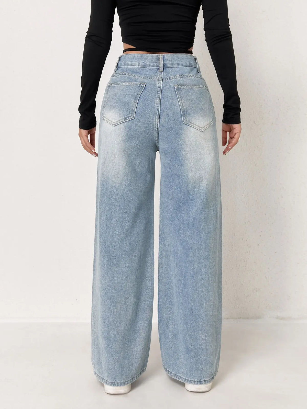 Light wash, high-waisted wide-leg denim jeans with a relaxed fit, worn with a black long-sleeve top.