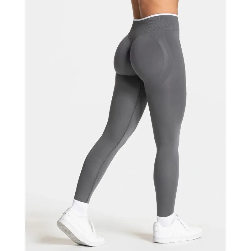 High-waisted seamless leggings in gray with a fitted silhouette, featuring contrast stitching and a wide waistband.