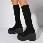 Ultra-chunky black platform boots with a curved block heel, extending to the knee for a bold gothic style.