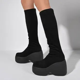 Ultra-chunky black platform boots with a curved block heel, extending to the knee for a bold gothic style.