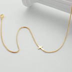 Delicate gold tone necklace featuring a minimalist cross pendant on a sleek chain, designed for effortless layering.