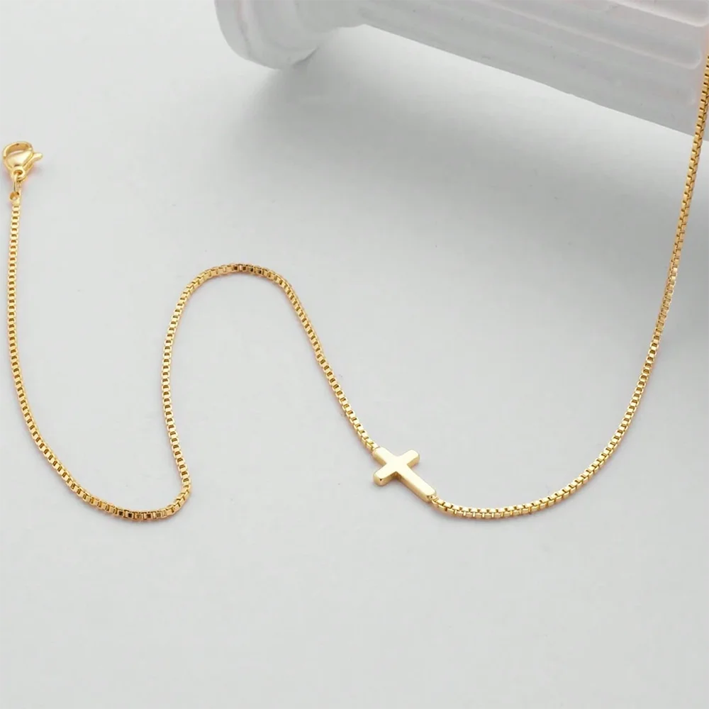 Delicate gold tone necklace featuring a minimalist cross pendant on a sleek chain, designed for effortless layering.
