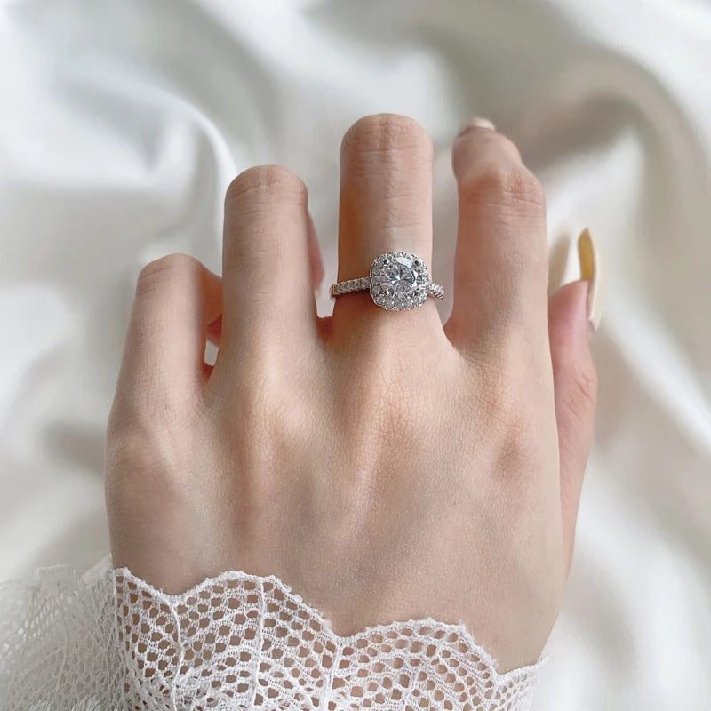 Luxury halo Moissanite statement ring displayed on a hand, featuring a round-cut center stone surrounded by smaller crystals.