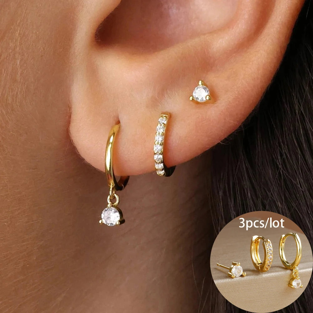 Asymmetric gold-toned earring set featuring a dangling rhinestone, a pavé hoop, and a small stud.
