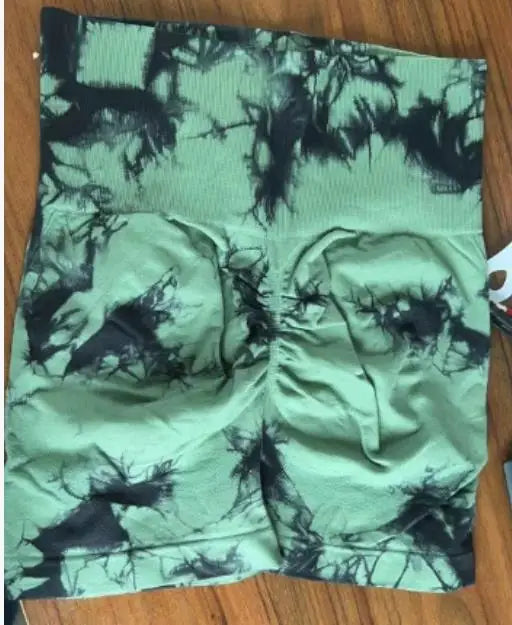 High-waisted gym shorts with a green and black tie-dye pattern, featuring a scrunch detail at the back for a flattering fit.