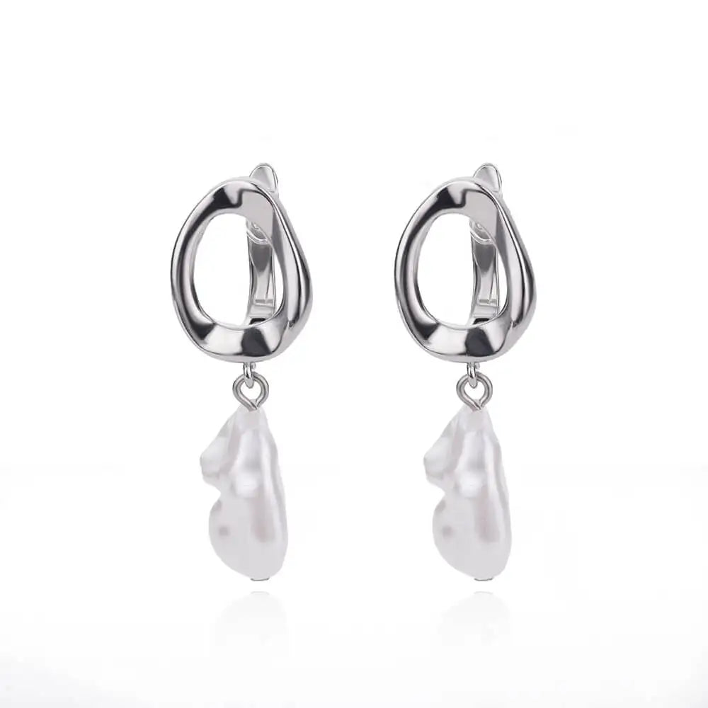 Chunky silver huggie earrings featuring a dropped white heart-shaped drop, designed for a modern, minimalist look.