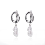 Chunky silver huggie earrings featuring a dropped white heart-shaped drop, designed for a modern, minimalist look.
