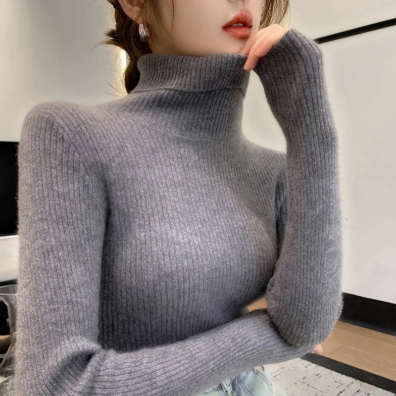 Slim-fit turtleneck sweater in soft gray cashmere, featuring ribbed texture and high collar, worn casually with a relaxed pose.