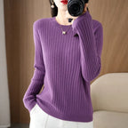 Cozy purple ribbed sweater with a crewneck collar, long sleeves, and a relaxed fit, styled with white pants.