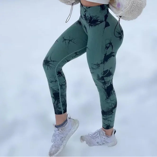 High-waisted green leggings with black abstract pattern, featuring a seamless design and a compression fit.