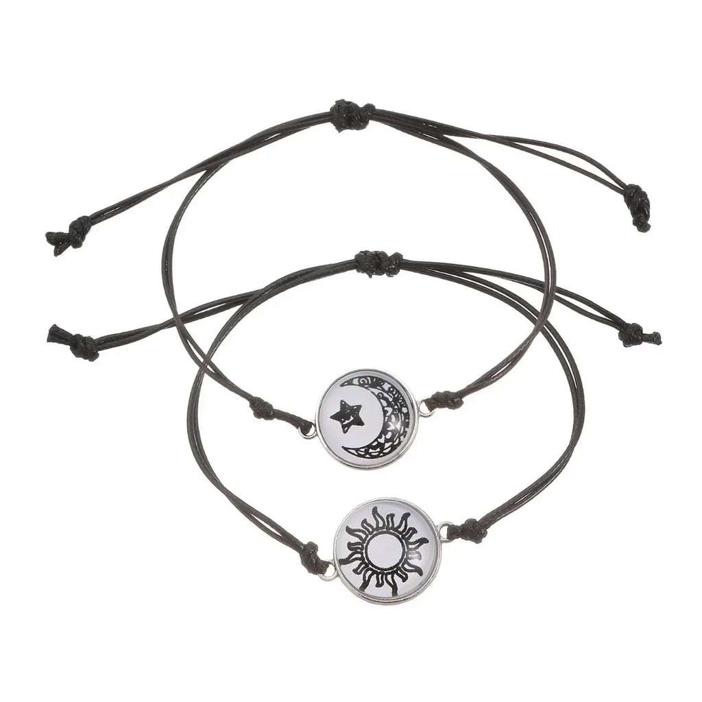 Two matching glow-in-the-dark bracelets with minimalist rope chains, featuring a moon and sun emblem on each.