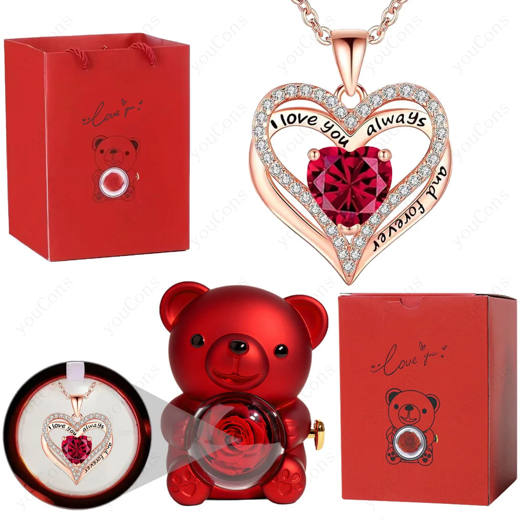 Red heart pendant necklace with a crystal center, surrounded by sparkly accents, displayed with a red bear figure and gift box.