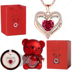 Red heart pendant necklace with a crystal center, surrounded by sparkly accents, displayed with a red bear figure and gift box.
