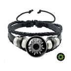 Multi-layered black leather bracelet with a sun token, featuring braided detailing and silver-tone accents.