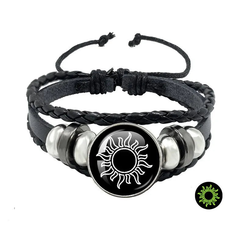 Multi-layered black leather bracelet with a sun token, featuring braided detailing and silver-tone accents.
