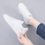 White LOVORA™ Blossom sneakers with floral embroidery, displayed at a slight angle and worn with denim jeans.