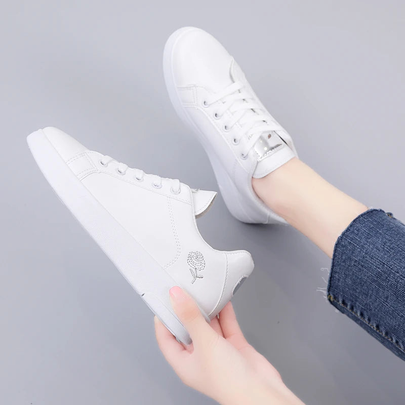 White LOVORA™ Blossom sneakers with floral embroidery, displayed at a slight angle and worn with denim jeans.