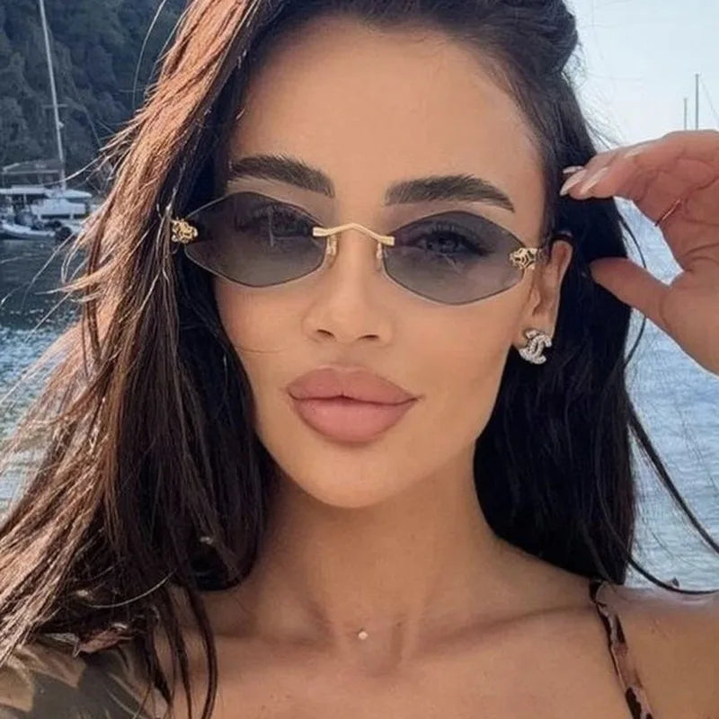 Rimless sunglasses with narrow geometric rhombus lenses and slender gold metal temples, worn by a model with long dark hair.