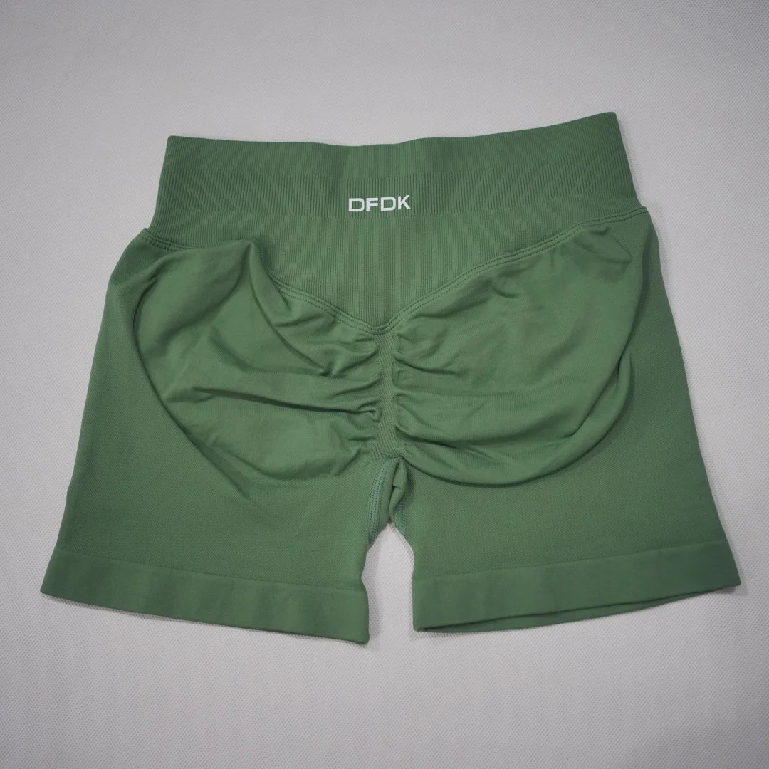 High-waisted, seamless gym shorts in a deep green color with a scrunch-butt design and wide waistband for support.