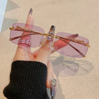 Rimless Y2K rectangle sunglasses with purple gradient lenses and metallic hinges, held between fingers, featuring gold accents.