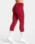 High-waisted red seamless leggings feature a contouring design and a wide waistband, styled with white sneakers and socks.