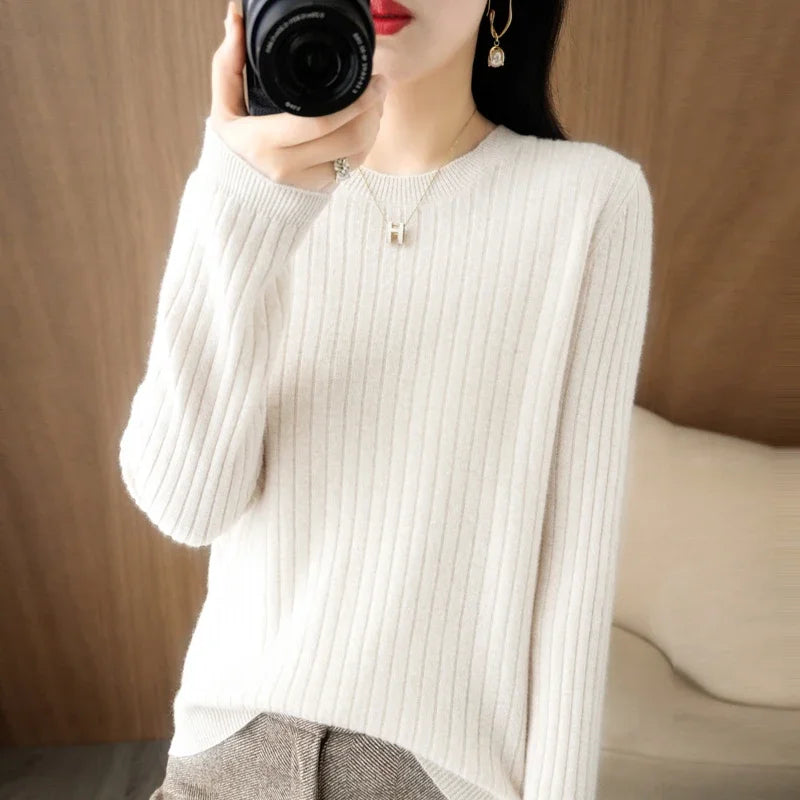 Classic striped pullover in soft cream, featuring a ribbed crewneck and relaxed fit, worn over stylish trousers.