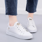White premium sneakers with floral embroidery, featuring a lace-up design and soft ankle collar, paired with cropped blue denim jeans.