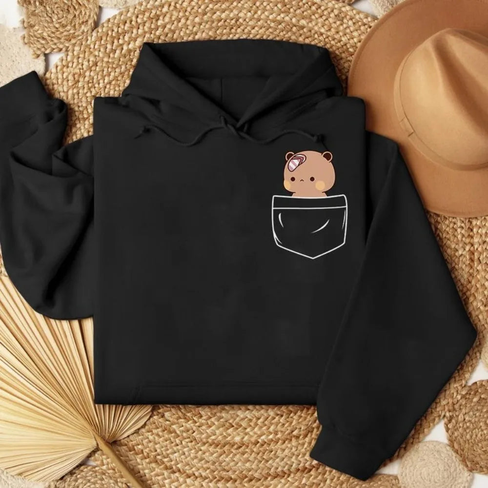 Oversized black hoodie featuring a playful bear graphic in a pocket design, with a soft fleece interior and ribbed trims.